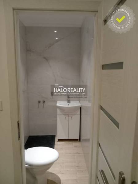 A bathroom in a 3-room apartment with marble-patterned tiles and walls.