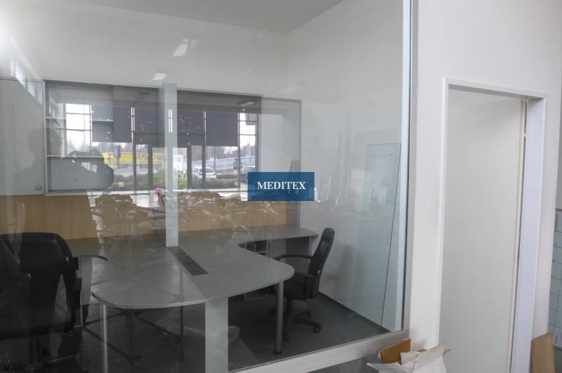 A glass-walled office with furniture and windows in commercial premises.