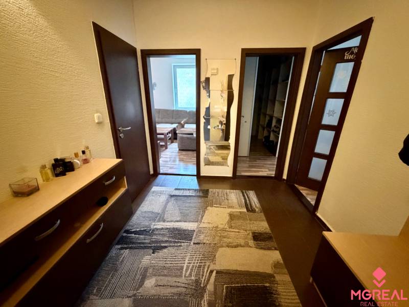 The entrance hall of a 3-room apartment with a wooden decor floor and a carpet.