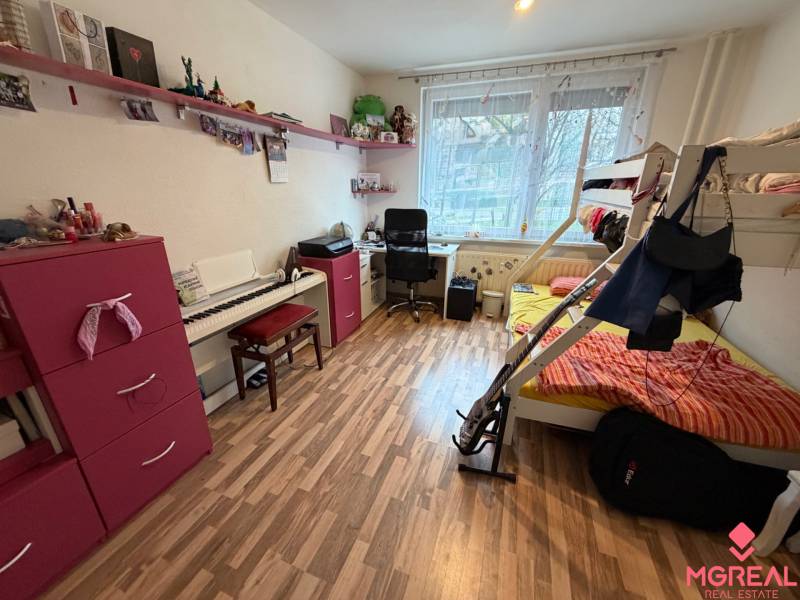 A room in a 3-room apartment with a bunk bed, a desk, and a floor with a wooden decor.
