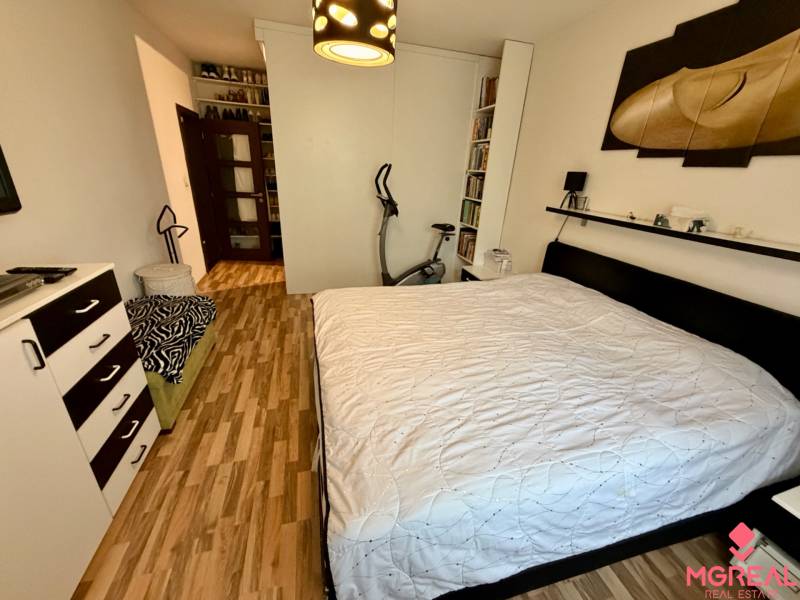 Bedroom with a double bed and a wooden decor floor in a 3-room apartment.