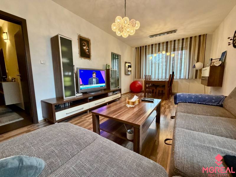 Living room in a three-room apartment with a wooden decor floor and a comfortable sofa.
