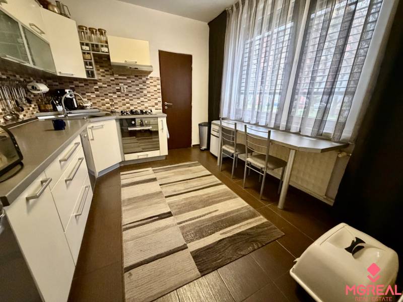 A kitchen in a 3-room apartment with a dark floor and a large window.