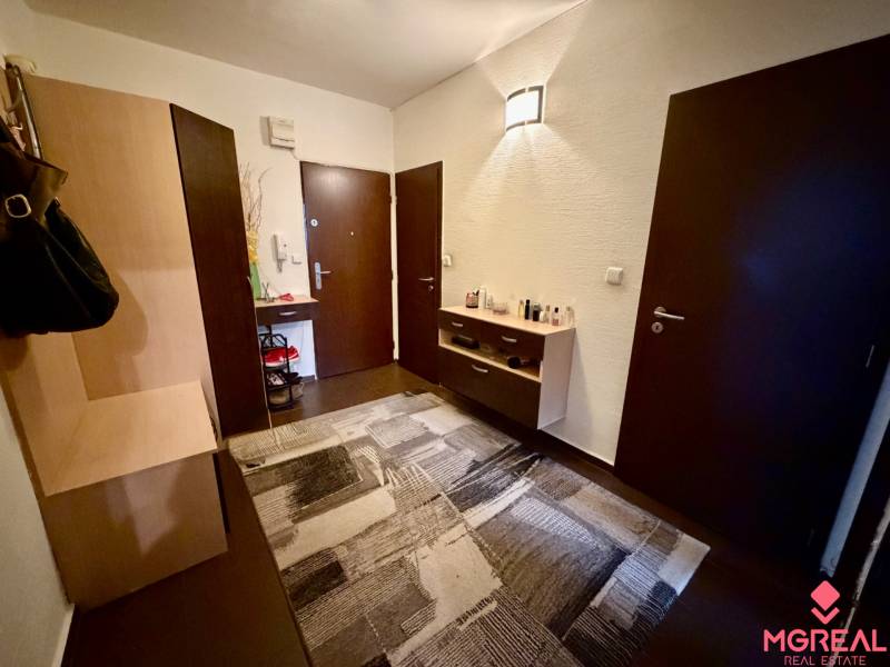 A hallway with dark doors, a chest of drawers, and a wooden decor floor in a 3-room apartment.
