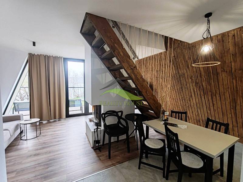 A cottage with a wooden decor floor, a staircase, and a table next to a wall of wooden slats.
