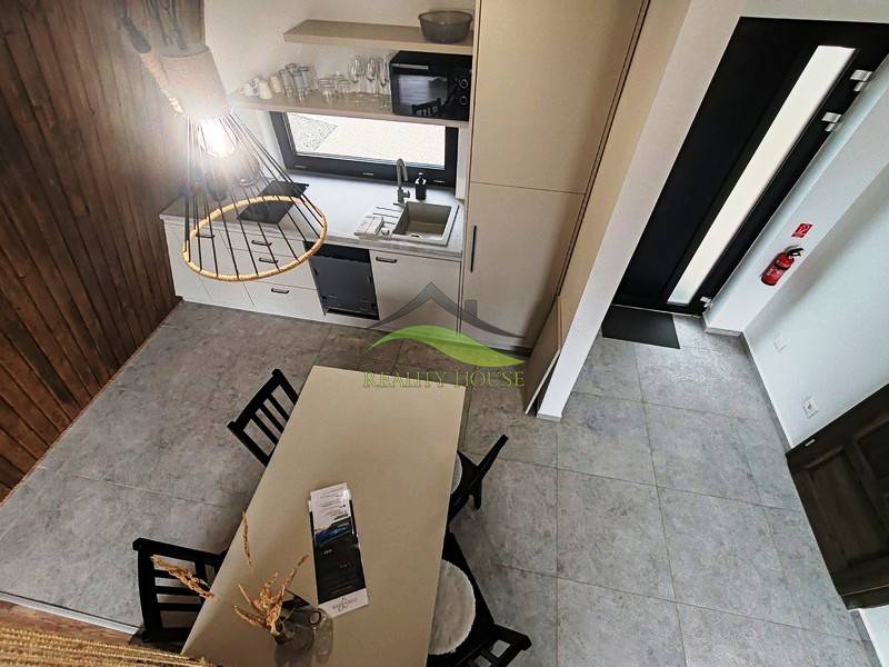 The interior of the cabin with a dining table, kitchen counter, and wooden floor decor.