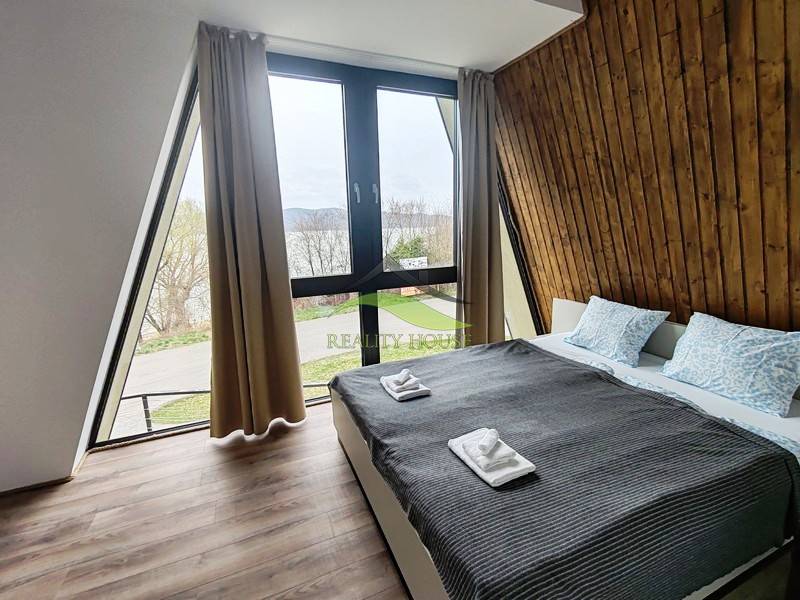 A room in a cabin with a view, a bed, and a wooden decor floor.