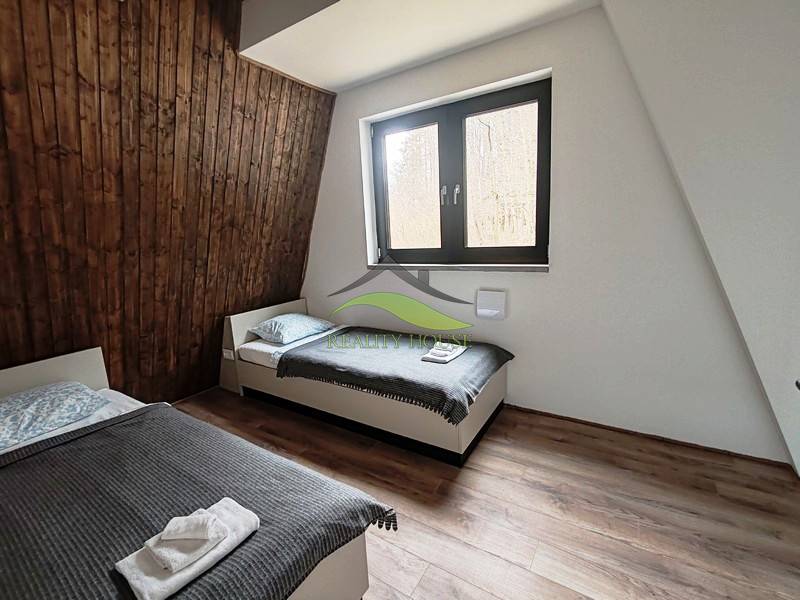 A room with two beds, wooden paneling, and a floor with a wooden decor in a cabin.