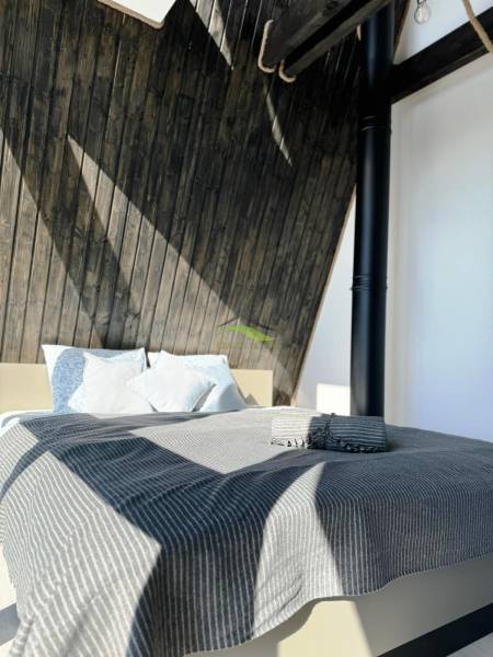 A bed with a striped blanket and wooden walls in a cabin.