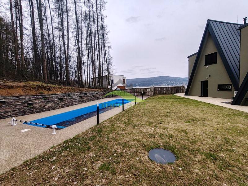A cottage on Evy Street in Holčíkovce with a pool and lawn surrounded by forest.