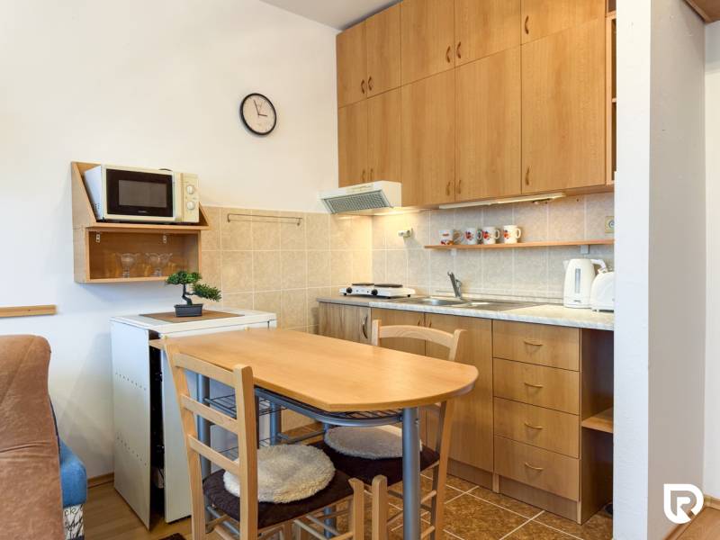 Studio apartment with a kitchenette, table and chairs, wooden decor flooring.