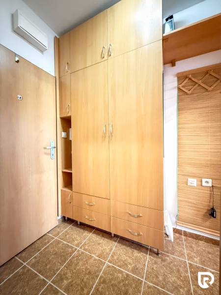 The studio apartment has a built-in wardrobe with a wood decor and tiled flooring.