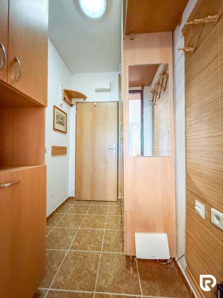 Entrance hall in a studio apartment with tiles, wardrobes, and a mirror, wood decor.