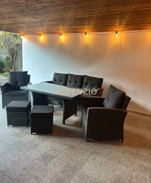 Outdoor seating with rattan furniture and lights on the terrace.
