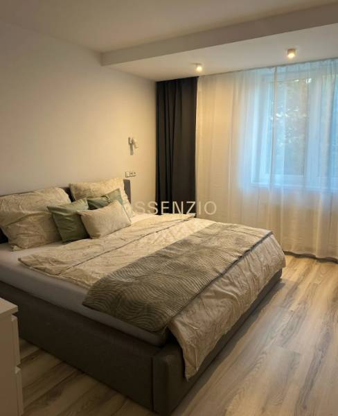 A bedroom in a two-room apartment with a bed and a floor with a wooden decor.