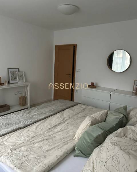 Bedroom in a 2-room apartment with white furniture and a bed with pillows.