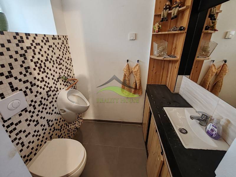 A bathroom in a family house with a sink, mirror, and mosaic tiles.