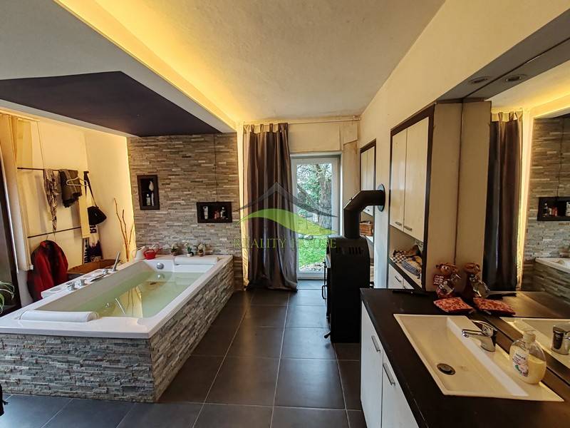 Spacious bathroom with a bathtub and tiles in a family house, floor with wood decor.