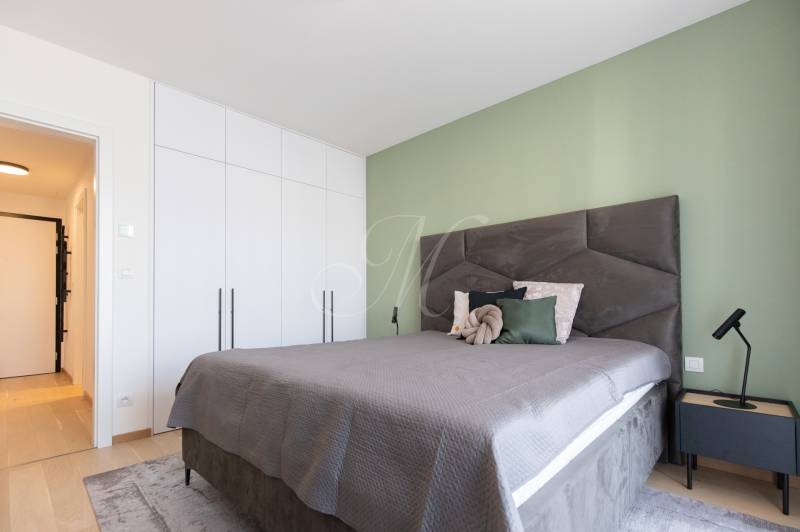 A bedroom with a bed, light built-in wardrobes, and a nightstand in a two-room apartment.