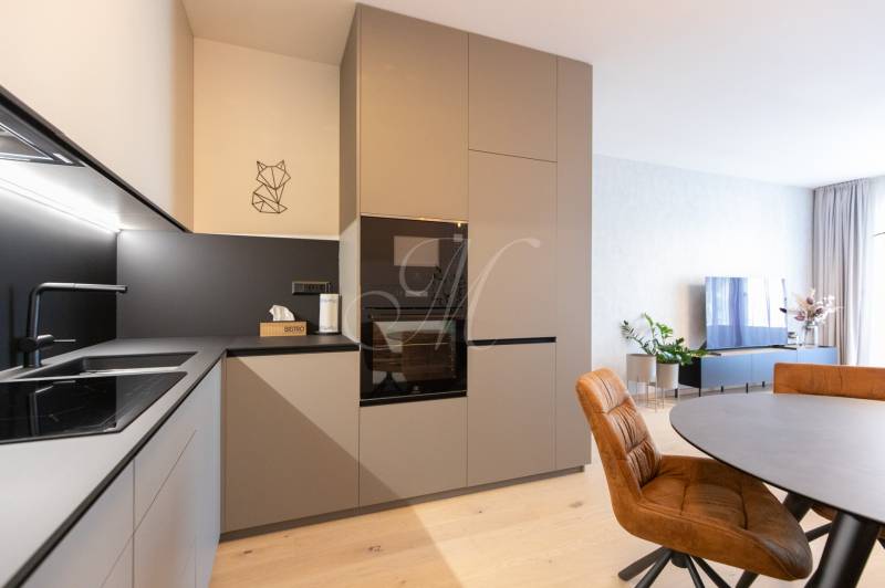 A kitchen unit with electrical appliances and a dining table in a 2-room apartment, floor with wooden decor.