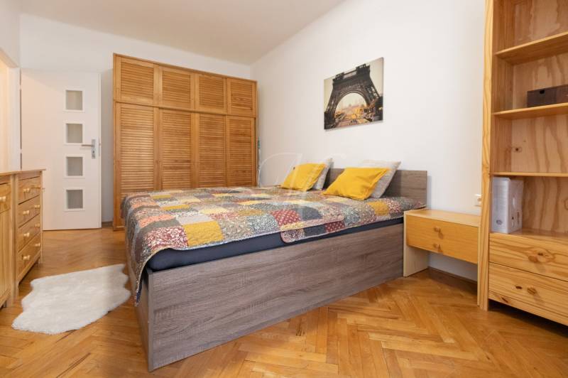 Bedroom in a 2-room apartment with a bed, wooden wardrobe, and floor with a wooden decor.