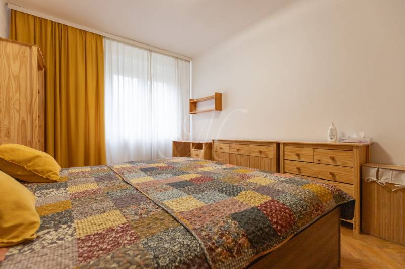 A bedroom in a two-room apartment with yellow curtains and wooden furniture.