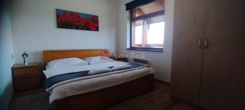 Bedroom with a double bed, a picture of flowers, and a wardrobe in a two-room apartment.