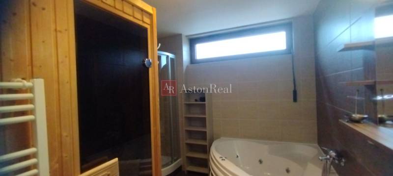 A bathroom with a bathtub, shower, sauna, and window in a 2-room apartment.