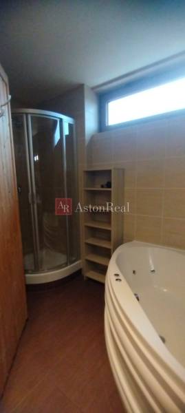 Bathroom with a shower, corner bathtub, and floor with wood decor in a 2-room apartment.