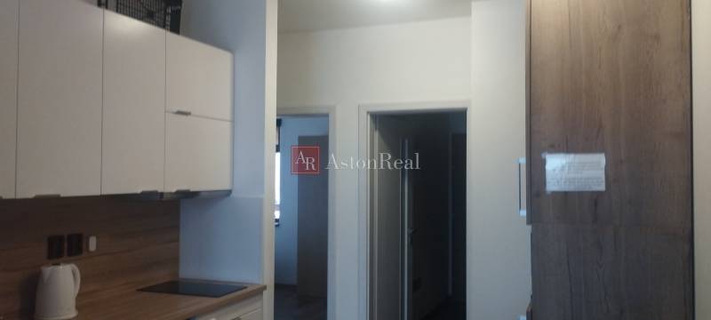 A kitchen with white cabinets and wood decor in a 2-room apartment.