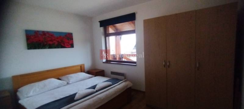 Bedroom with a double bed, wooden decor flooring, and a wardrobe in a 2-room apartment.