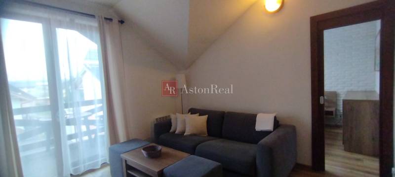 Living room in a two-room apartment with a sofa, coffee table, and glass doors to the balcony.