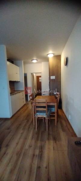 Dining room in a 2-room apartment with a wooden decor floor and a wooden table.