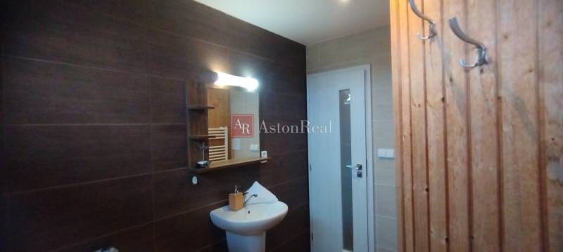 Bathroom in a 2-room apartment with dark tiles, a mirror, and a white washbasin cabinet.