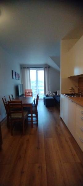 Kitchen corner with a dining table and floor with wood decor in a 2-room apartment.