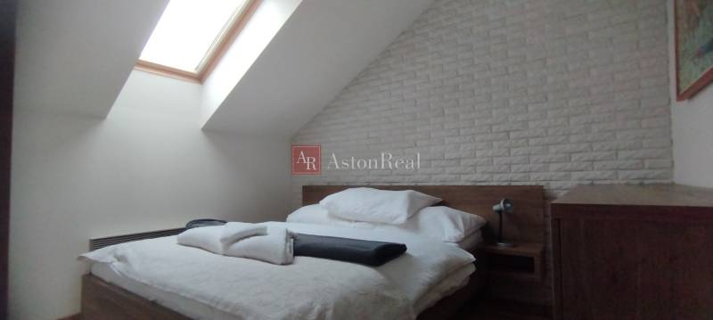 A bedroom in a 2-room apartment with a bed, a skylight, and a brick cladding.