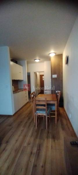 Interior of a 2-room apartment with a wooden decor floor and a dining table.