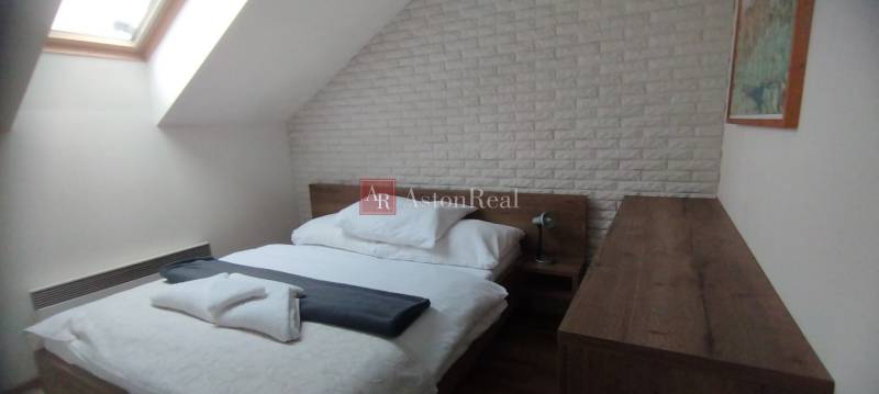 Bedroom with a bed and a skylight in a 2-room apartment with decorative brick cladding.