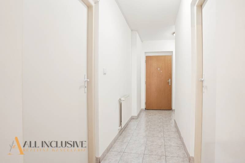 A corridor with white walls, tiles, and wooden doors in a 2-room apartment.