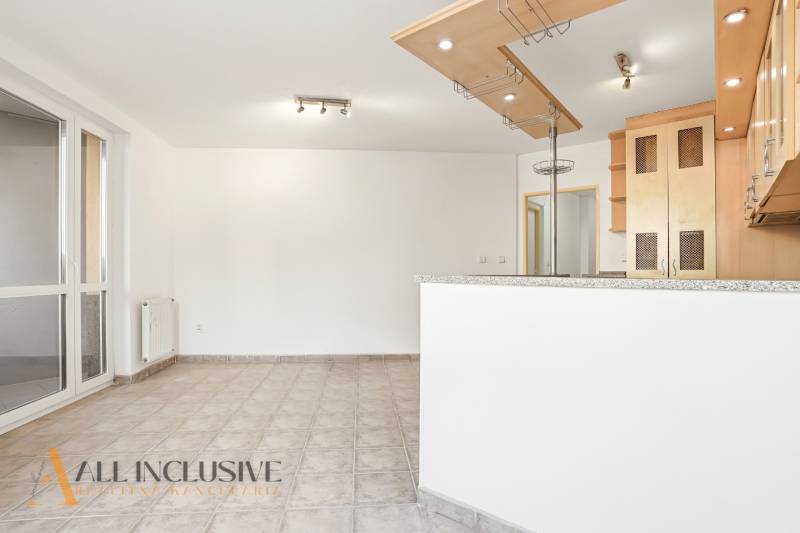 A kitchen in a 2-room apartment with a tiled floor and wooden cabinets.