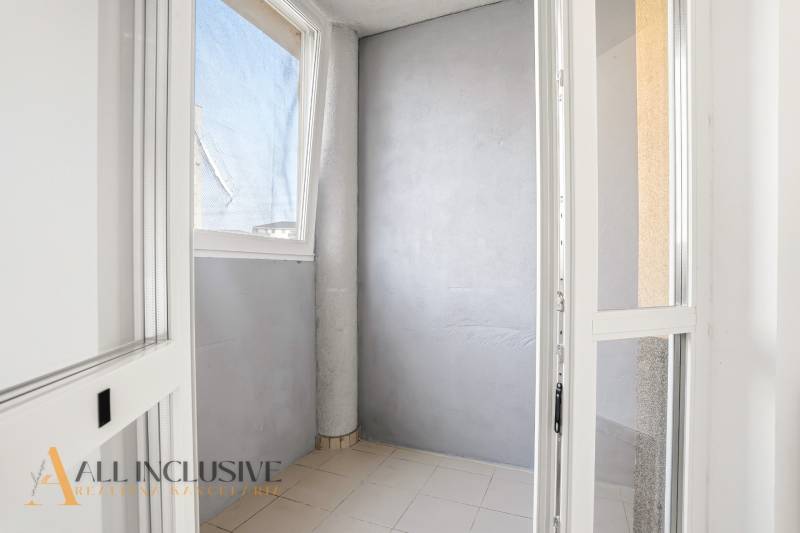 Glazed balcony wall in a 2-room apartment with simple tiles and gray walls.