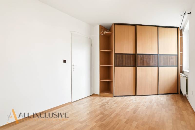 White interior with a large wardrobe and wooden decor flooring in a 2-room apartment.