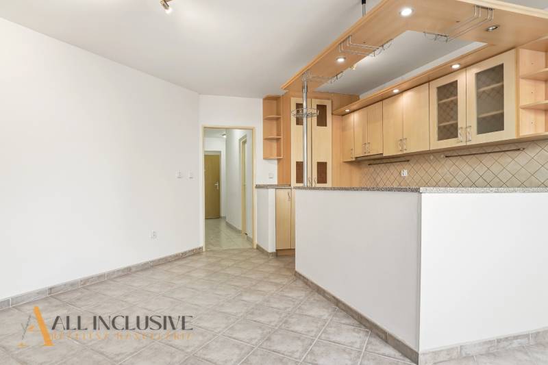 A kitchen in a 2-room apartment with white walls and tiled flooring.
