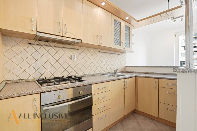 A kitchen in a 2-room apartment with a gas stove and light kitchen cabinets.
