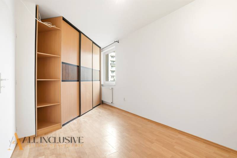 A room in a 2-room apartment with a wood-decor floor and a built-in wardrobe.
