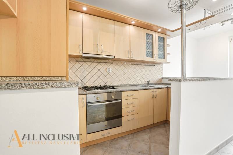 A kitchen in a 2-room apartment with wooden cabinets and a stone countertop.