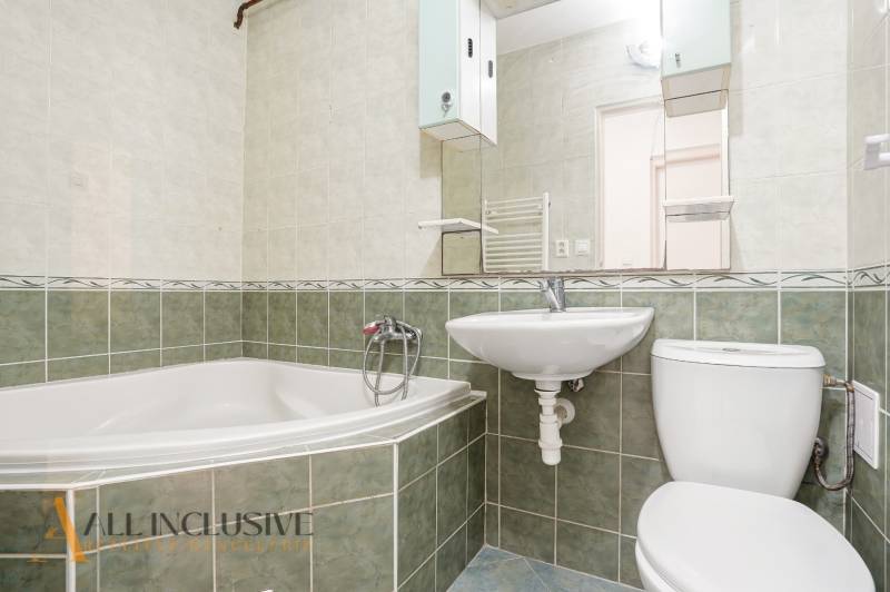 A bathroom in a 2-room apartment with a bathtub, sink, and toilet, tiled with green tiles.