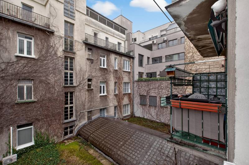 A view of the courtyard of apartment buildings with old plaster and a balcony.