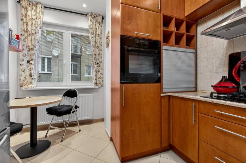 A kitchen in a 3-room apartment with a dining area and wooden cabinet decor.