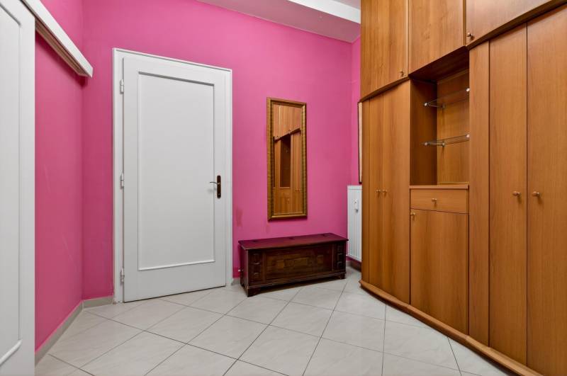 A hallway in a 3-room apartment with pink walls, white doors, and a wardrobe.
